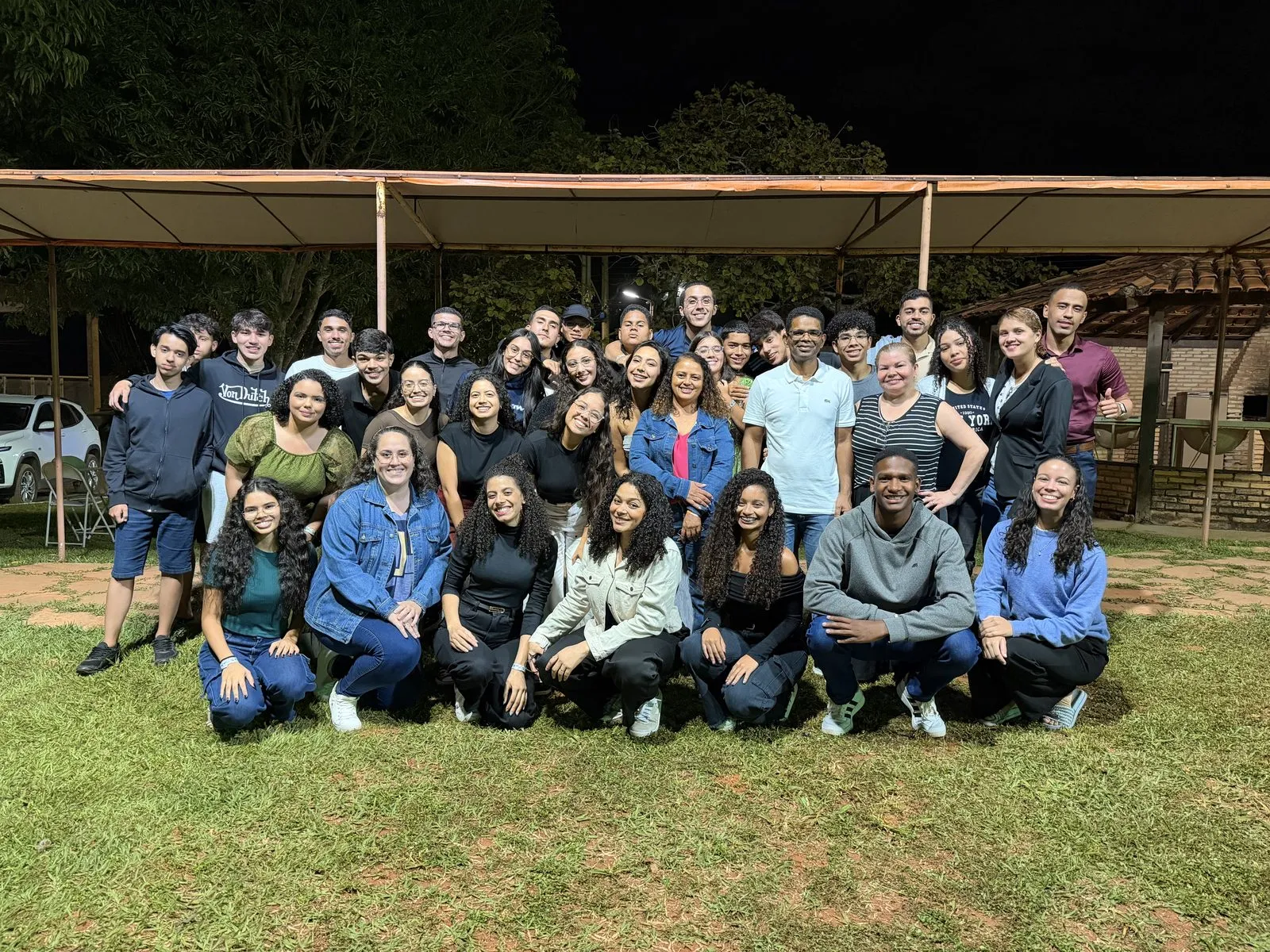 O grupo de jovens reunido para uma foto ao ar livre, à noite